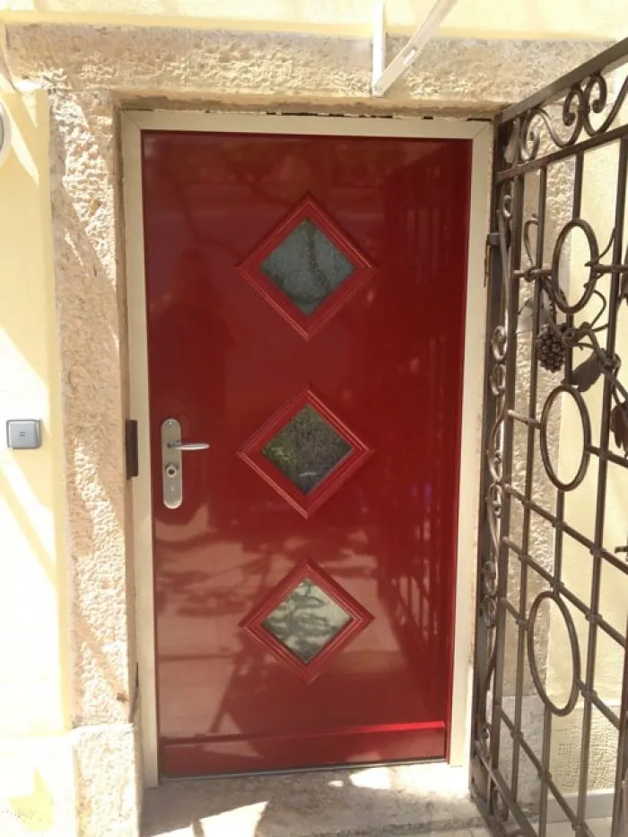 pm3 Porte rouge vitrée derrière une grille d’entrée